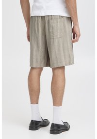 Beige gestreifte Shorts mit elastischem Bund und einer Gesäßtasche, aus weichem Stoff, mit entspanntem Schnitt und knielangem Design.
