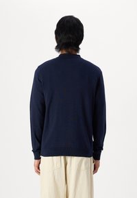 Maglione a maniche lunghe color blu navy con polsini e orlo a coste, realizzato in tessuto morbido, dotato di un classico design con collo a girocollo.