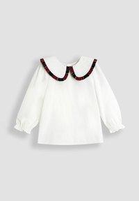Blusa bianca a maniche lunghe con colletto tondo, caratterizzata da un bordo arricciato bordeaux e nero. Polsini elasticizzati e una chiusura semplice sul retro.