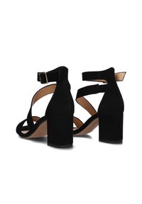 Zwarte suède sandalen met hakken, voorzien van een blokhak, met kruislings gespen en een enkelgesp voor een veilige pasvorm en stabiliteit.