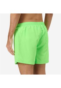 Costumi da bagno verde neon con vita elasticizzata, texture liscia e una singola tasca posteriore sul lato destro.