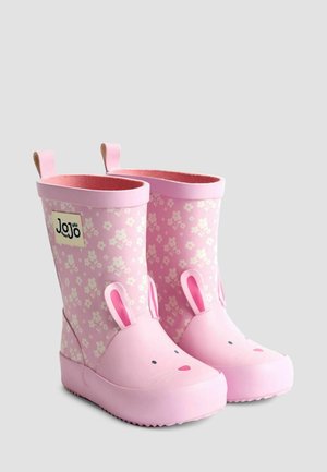 Rozā bērnu lietus zābaku pāris, rotāts ar baltām ziedu un trušu sejām ar ausīm priekšpusē.