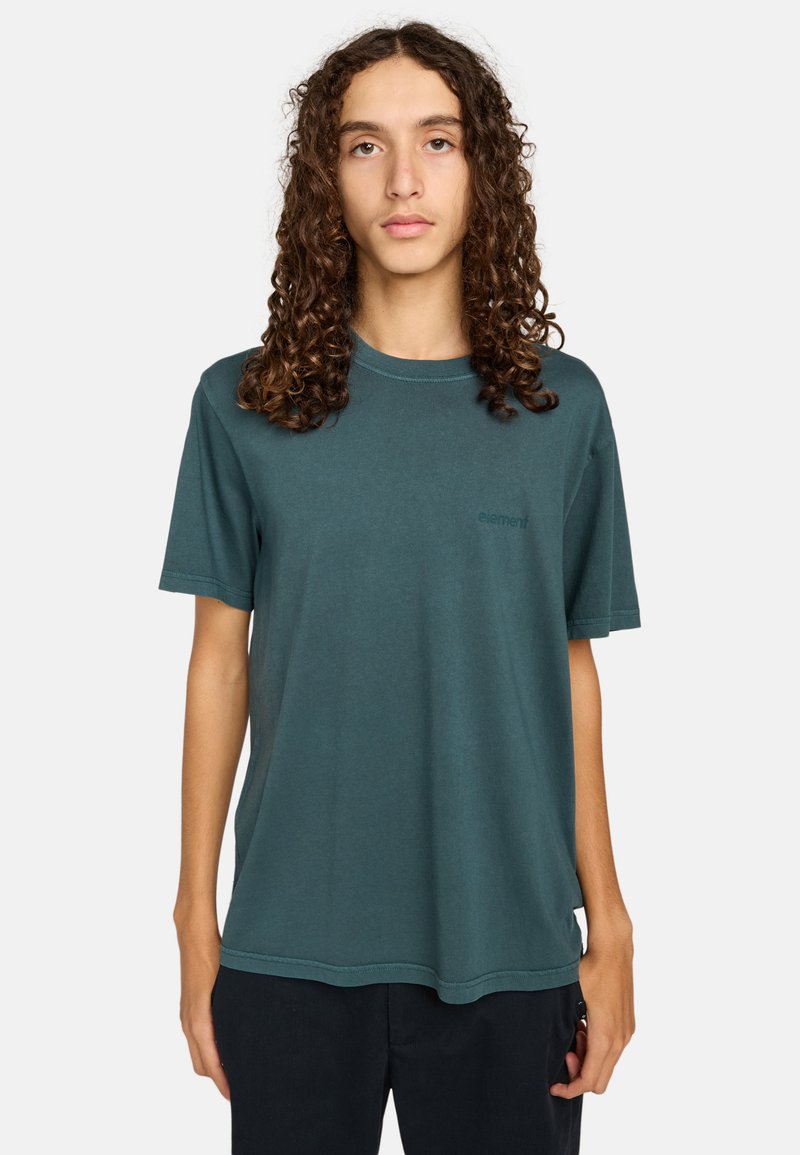 Camiseta de manga corta color teal oscuro hecha de algodón suave. Presenta un cuello redondo y un pequeño logo impreso en el lado izquierdo del pecho. Dobladillo redondeado.