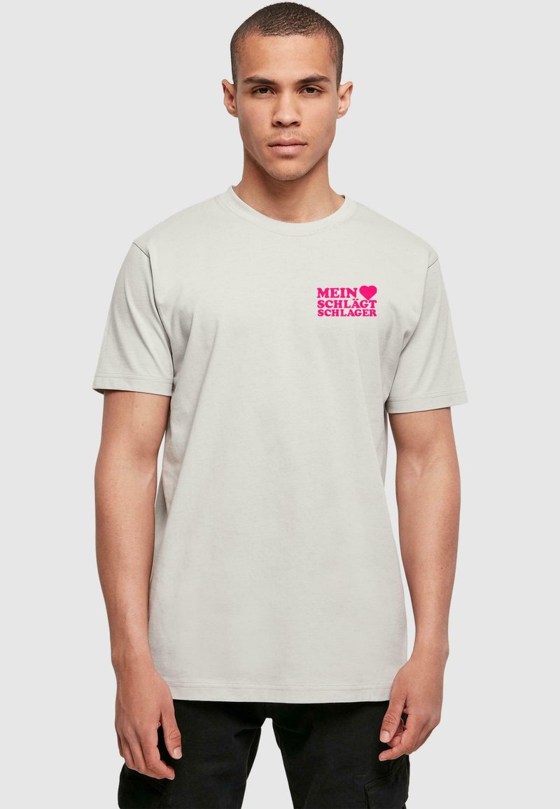 Grå kortærmet t-shirt lavet af bomuld, med et pink grafisk print på venstre bryst med teksten "MEIN ♥ SCHLÄGT SCHLAGER."