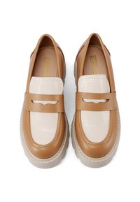 Mocassini in pelle beige e crema con finitura testurizzata, caratterizzati da una suola piatta e spessa e una fascia decorativa lungo l'arco del piede.