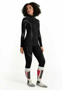 Ensemble de couche de base thermique noire avec un col montant, présentant des accents et des motifs gris. Comprend des chaussettes montantes avec des détails rouges et gris.