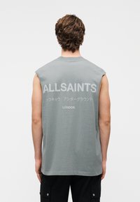 Αμάνικη γκρι μπλούζα με μεγάλο κείμενο "ALLSAINTS" και "LONDON" στην πλάτη, κατασκευασμένη από απαλό βαμβάκι με λεία υφή.