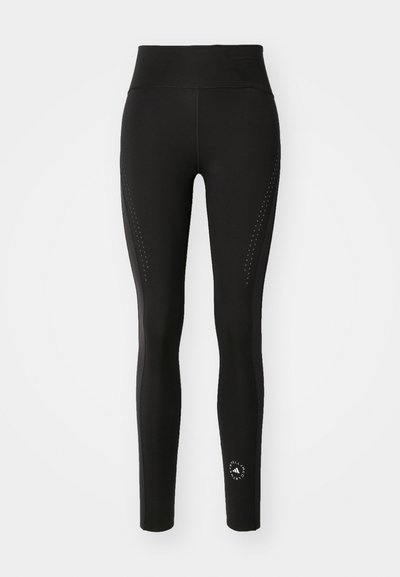 Black leggings with a high waistband, featuring perforated detailing on the sides and a small logo at the ankle. Smooth, stretchy fabric.