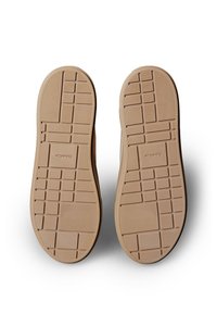 Tan rubberen zolen van schoenen met een gestructureerd, patroonontwerp. Voorzien van een raster en lijnen voor grip, gemarkeerd met het merk "Calvin Klein."