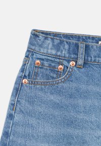 Τζην παντελόνια από denim με ανοιχτό μπλε ξέπλυμα, με χαλκοχάλκινα καρφιά, σχεδιασμό με πέντε τσέπες και εμφανείς ραφές στη μέση και στις τσέπες.