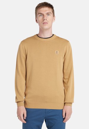 Maglione marrone chiaro con collo a girocollo e polsini a coste, caratterizzato da una piccola etichetta con il marchio sul petto. Tessuto morbido, design lavorato a maglia.