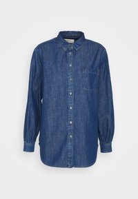 Pitkähihainen sininen farkkupaita, jossa edessä napit, vasen rintatasku ja kauluksellinen pääntie, yksivärisellä valkoisella taustalla.