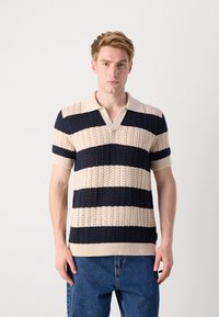 Polo din tricot în nuanțe de bej și bleumarin cu dungi orizontale, având guler în V, mâneci scurte și un model texturat pe întreaga suprafață.