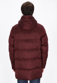 Burgundský puffer kabát s kapucí, vybavený prošívanými panely a hladkou texturou. Kabát sahá do poloviny stehna, poskytuje pokrytí a teplo.