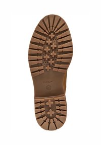 Suela de zapato de goma marrón con profundas ranuras que presentan patrones en forma de cruz y "GEOX" y "patente italiana" grabados en el centro.