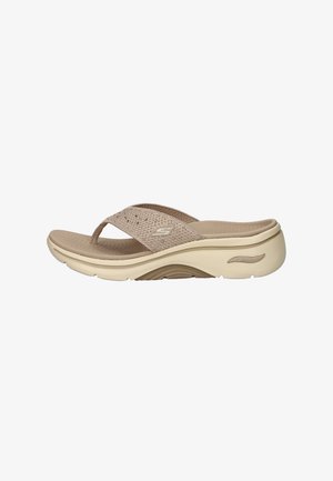 Beige Skechers Arch Fit sandal with textured footbed, cushioned sole, and woven fabric thong strap with logo on side.
