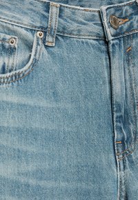 Svetlo modri kavbojke z rahlo zbledelim vzorcem, z oranžnim šivanjem, sprednjim žepom in srebrnim gumbom za zapiranje.