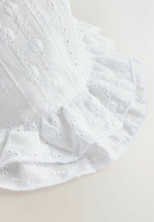 Hvidt broderet stof med blomsteragtige mønstre og flæset kant. Tekstureret overflade med dekorative syningdetaljer over det hele.