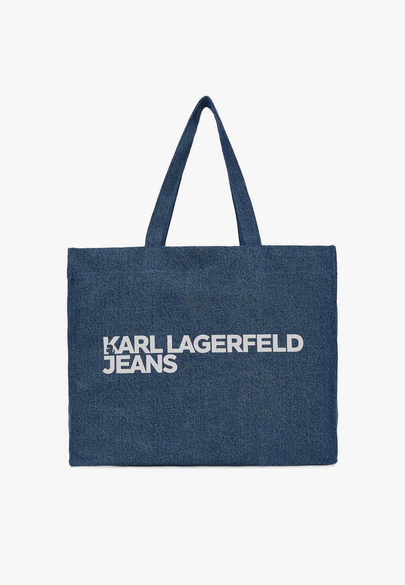 Sac fourre-tout en denim bleu foncé avec des poignées doubles et un grand texte blanc indiquant "KARL LAGERFELD JEANS." Design rectangulaire simple.