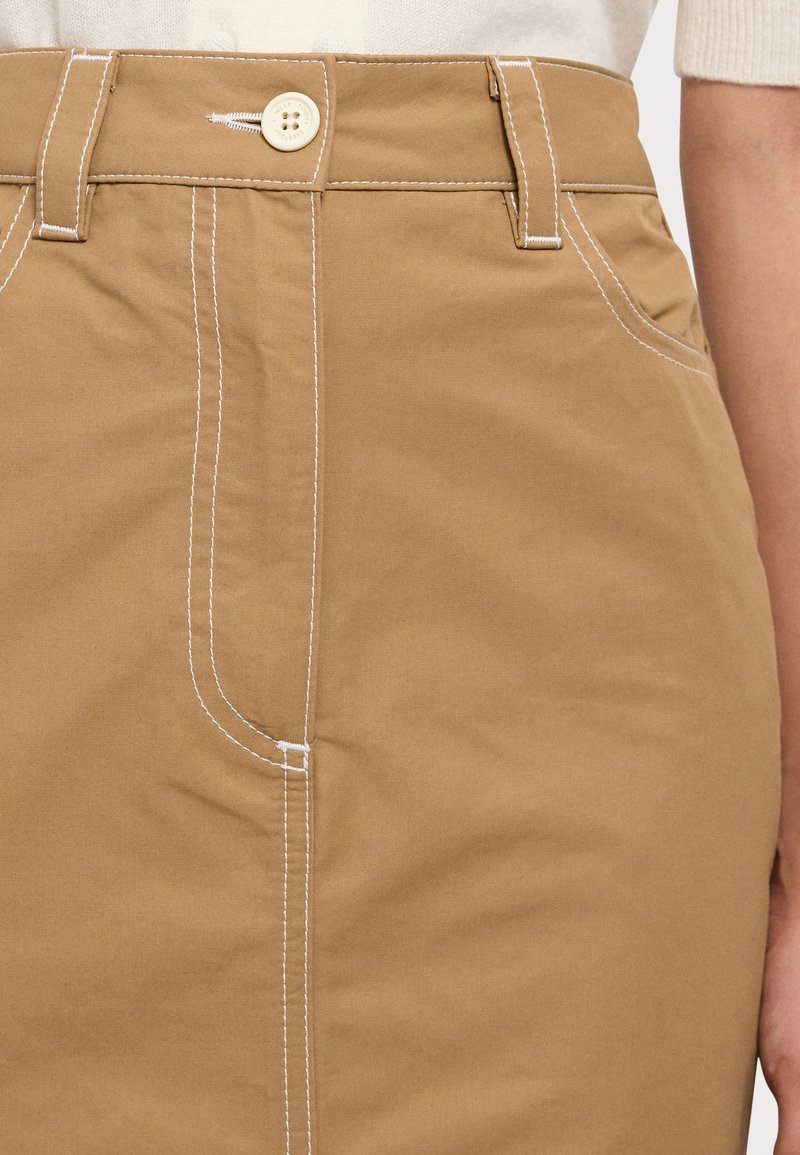 Falda de algodón de color tan con costuras blancas, cierre de botones en la parte frontal y un ajuste slim con bolsillos laterales.
