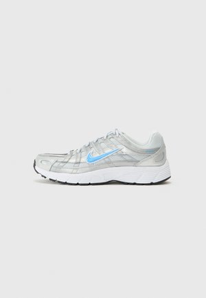 Chaussure de running Nike en argent avec une tige en mesh respirant, détails bleus et une semelle blanche dotée de crans noirs pour l'adhérence.