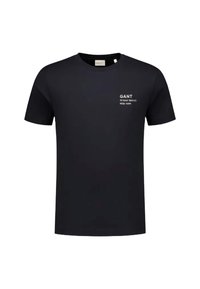 Camiseta negra de cuello redondo hecha de algodón, con una marca impresa en blanco en el lado izquierdo del pecho, mangas cortas y dobladillo recto.
