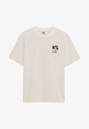 T-shirt à manches courtes de couleur blanc cassé avec un petit motif d'arbre de style japonais en noir et rouge et le texte "KAOTIKO SOCIETY" sur le côté gauche de la poitrine.