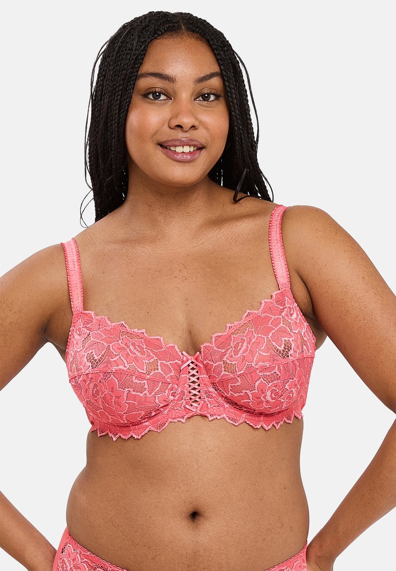Roze kant bralette met bloemmotieven, geschulpte randen en een decoratieve voorkant met vetersluiting. Gladde, verstelbare bandjes.