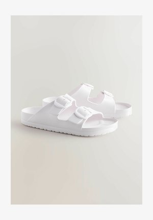 Hvide sandaler med to justerbare spænder, flad sål og et struktureret skridmønster. Fremstillet af letvægts, fleksibelt materiale.