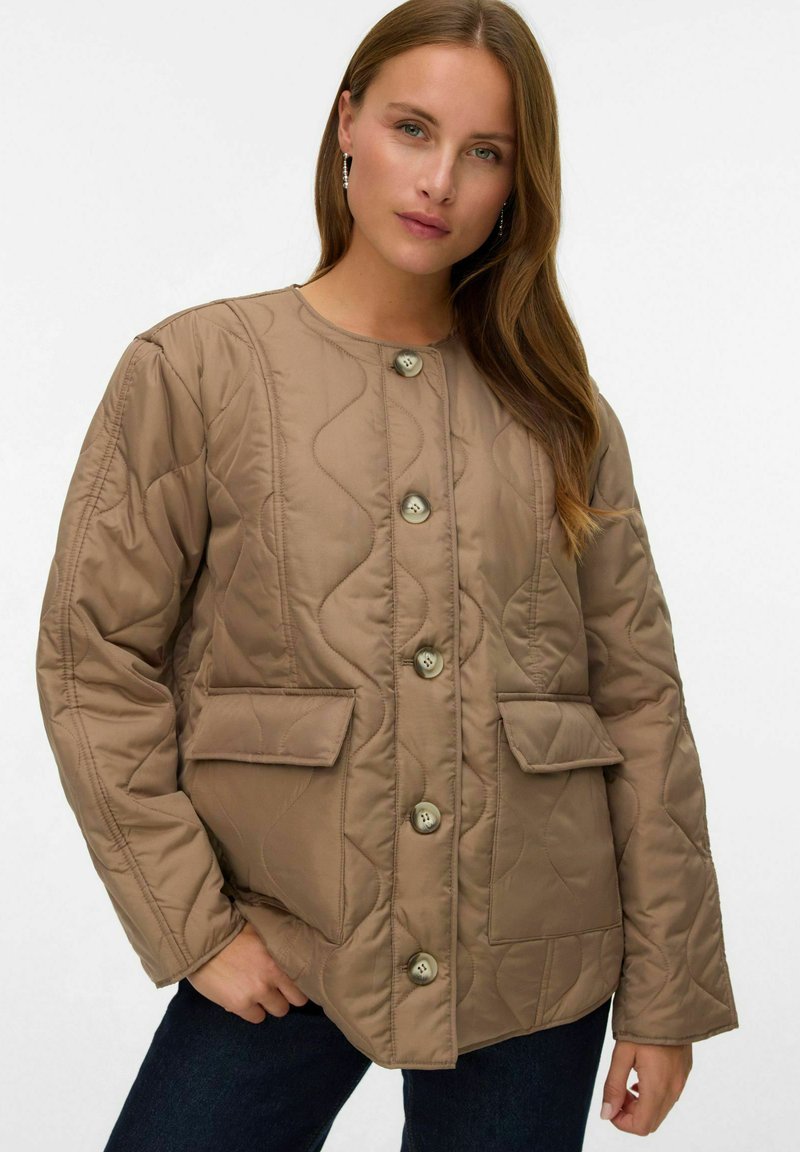 Kvadret beige jacka med rund halsringning, fyra knappar och två framfickor. Har en slät yta och accentuerande sömdetaljer.