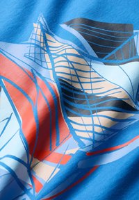 Țesătură albastră cu modele geometrice abstracte în roșu, negru și bej. Designul include linii și curbe pentru textură.