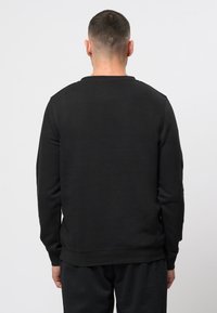 Zwarte sweatshirt van katoen, met een ronde hals, lange mouwen en een geribbelde onderrand. De achteraanzicht toont een gladde, egale textuur.