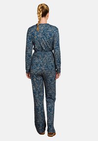 Blauer Blumen-Overall mit langen Ärmeln und taillierter Silhouette. Tolle Musterung kleiner Blumen, gefertigt aus weichstem Material.