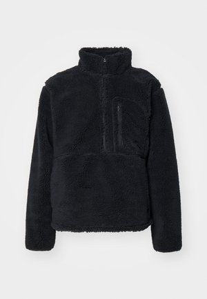 Zwarte pullover van zacht, getextureerd fleece. Voorzien van een hoge kraag, een gedeeltelijke rits en een ritsvak op de borst.