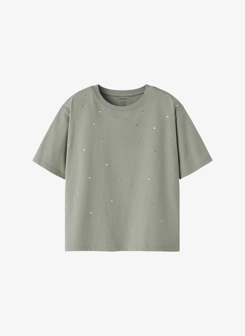 T-shirt vert clair à manches courtes avec de petits clous argentés dispersés et un col rond.