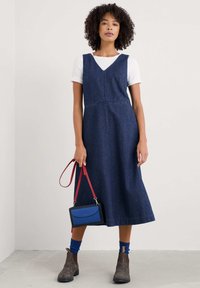 Denim-midi mekko V-aukolla, tummansininen väri ja tiukka yläosa. Yhdistetty punaisen olkahandbagin ja ruskeiden nilkkureiden kanssa.