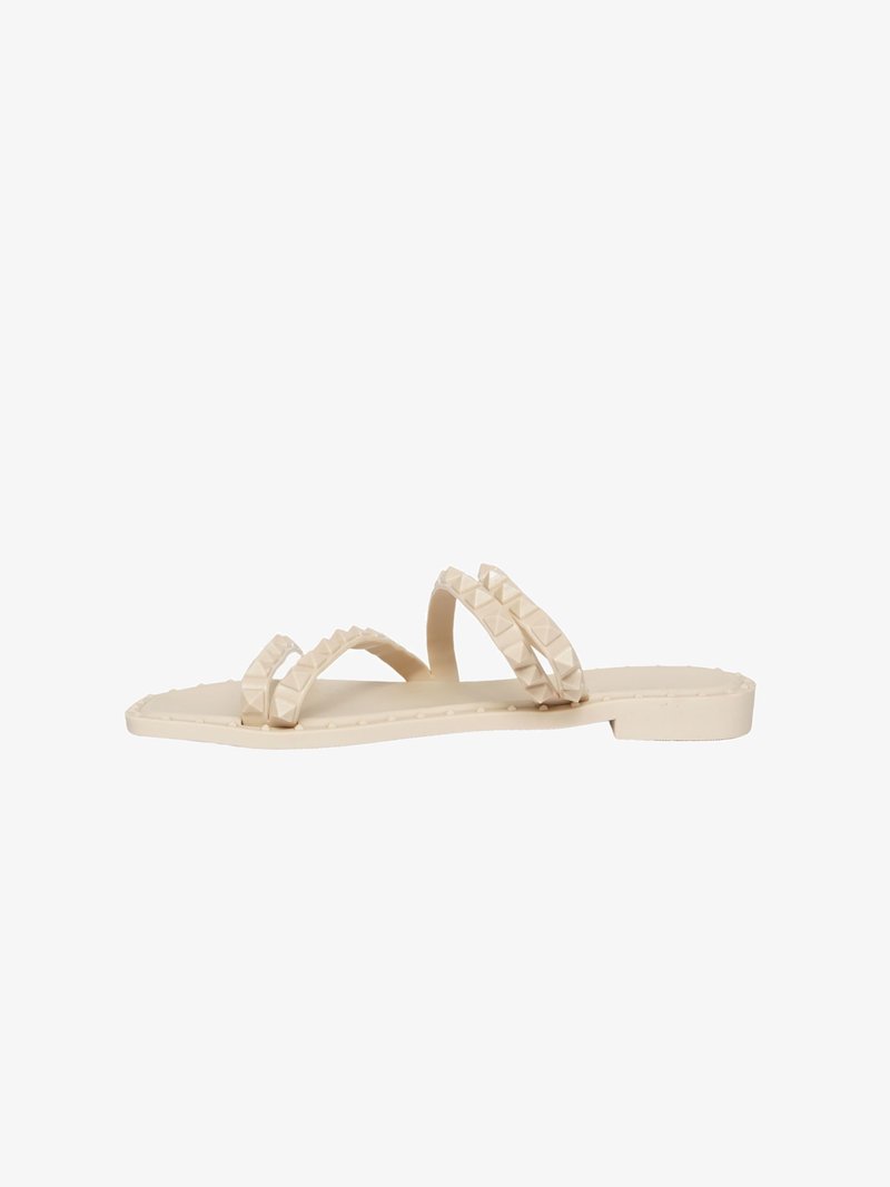 Sandali modellati beige con due cinturini testurizzati e dettagli a piramide, suola piatta e design minimalista. Adatti per un abbigliamento casual.