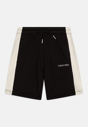 Shorts negros de algodón con un panel lateral blanco, cinturilla elástica, cordón y logo "Calvin Klein" en blanco en el frente.