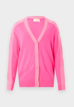 Ροζ ζακέτα με κουμπιά και πιο ανοιχτό ροζ περιθώριο κατά μήκος του γιακά, της σειράς κουμπιών και των μανικιών, παρουσιασμένη σε λευκό φόντο.