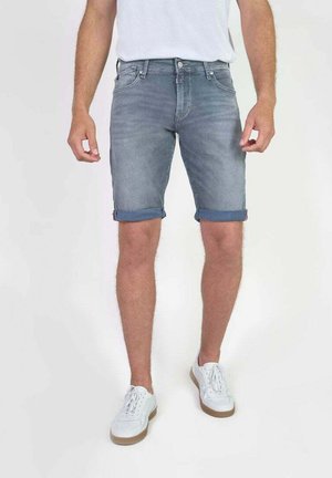 Shorts en denim bleu clair avec une finition délavée, présentant des revers roulés et un design classique à cinq poches, portés avec des baskets blanches.