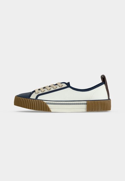 Χαμηλά λευκά sneakers με βαθύ μπλε περίγραμμα, μπεζ κορδόνια, καφέ καουτσούκ σόλα και διακοσμητικό μοτίβο ελληνικού κλειδιού κατά μήκος της μεσοσόλας.