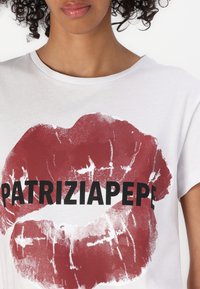 T-shirt bianco in cotone con un grande graphic di labbra rosse e testo bold nero che recita "PATRIZIA PEPE" su tutto il design.
