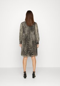 Abito camicia grigio con motivo a strisce zebrate testurizzate, maniche lunghe e vita cinchata. Presenta una chiusura a bottoni sul retro e maniche con polsini.