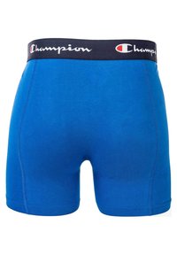 Modri bombažni bokserice z črnim elastičnim pasom, na katerem je bel logotip "Champion". Gladka tekstura, dolžina do sredine stegna, prilegajoča oblika.