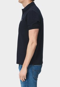 Mörkblå polo med klassisk krage, kort ärm och slim fit. Tillverkad i bomull med diskret logotypdetalj på bröstet.