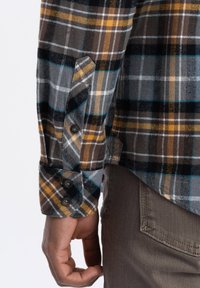 Flanellen overhemd met een geruit patroon in grijs, zwart, geel en blauw. Voorzien van een knoopmanchet en een zijzak. Het materiaal lijkt zacht en gestructureerd.