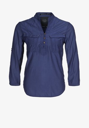 Mørkeblå langærmet skjorte med krave, to forlommer, tre brune knapper og subtile stikninger. Letvægtsstof, afslappet pasform.