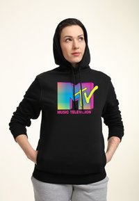 Černá mikina s kapucí a barevným logem MTV na hrudi, obsahující růžové, modré a žluté akcenty. Měkká tkanina a klasický střih.