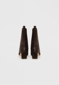 Rudos zomšos auliniai batai su kvadratiniu kulnu, turintys lygią apdailą ir užtrauktukus gale. Batai pasižymi elegantišku dizainu.