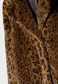 Brun kunstpelsfrakke med leopardmønster, der har en spids revers og en enkelt knaplukning, som fremhæver en blød, tekstureret overflade.